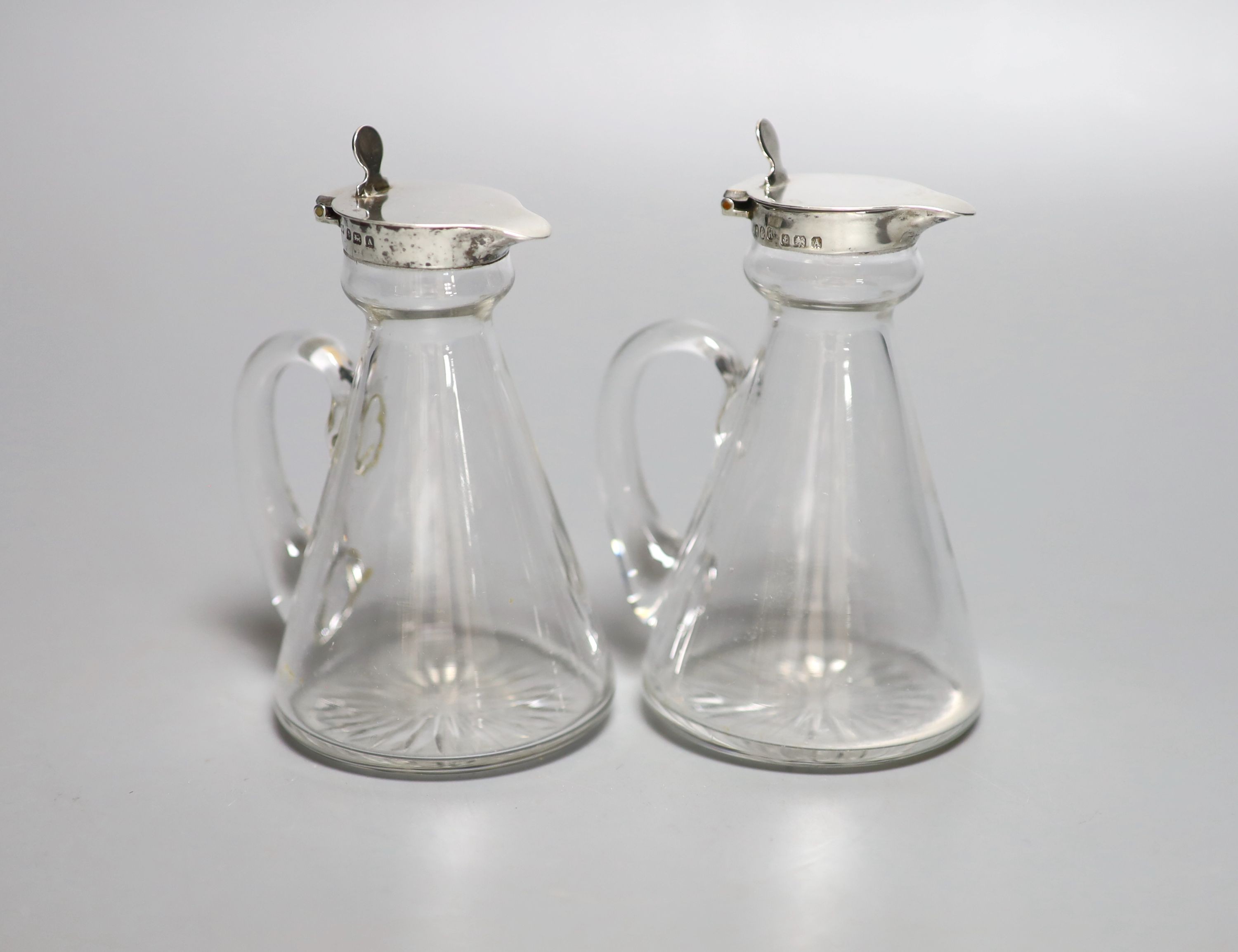 A pair of George V silver mounted glass whisky tot jugs, Hukin & Heath, Birmingham, 1925, 11.5cm.